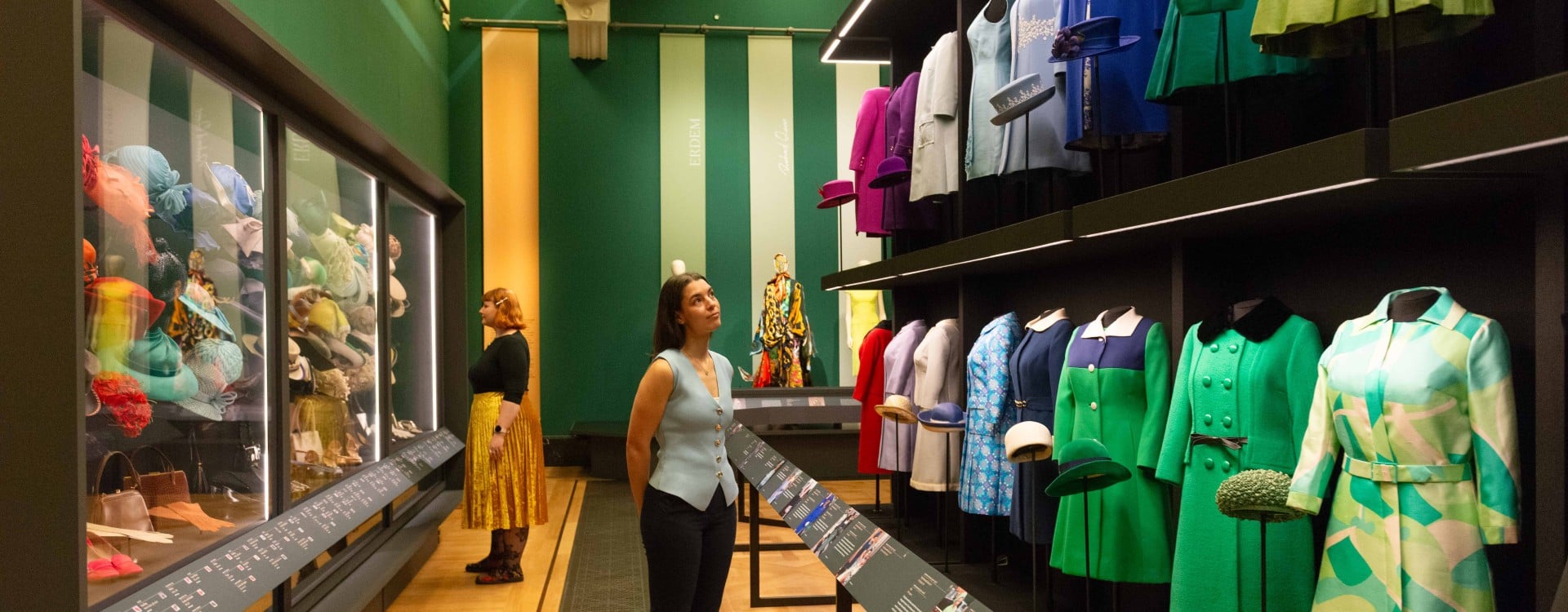 Visitors look at a display of colourful outfits in the exhibition Queen Elizabeth II: Her Life in Style