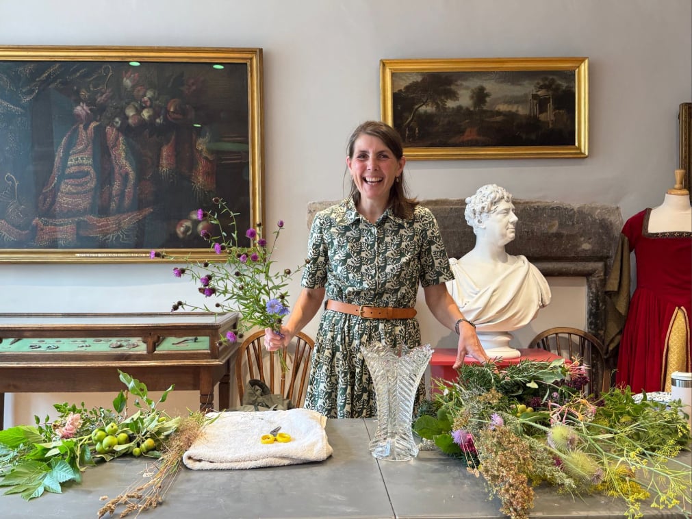 Florist Lottie Longman arranging flowers in a glass vase