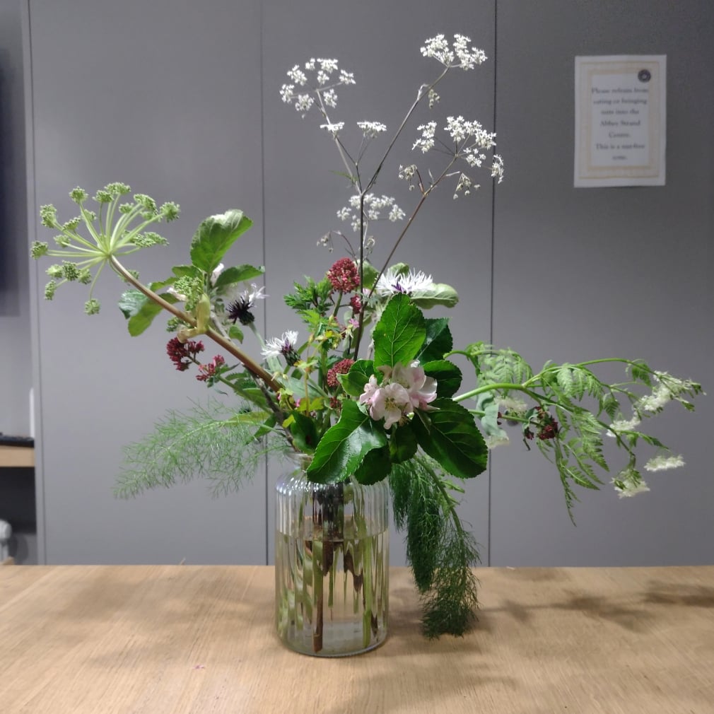 A vase of flowers sitting on a wooden desk