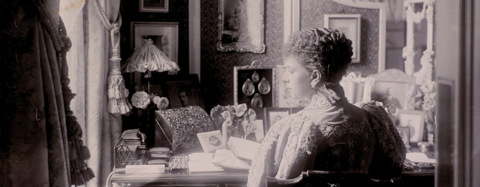 Princess Mary (later Queen Mary, 1867-1953) photographed at York House holding open a large book or album (RCIN 2808151)