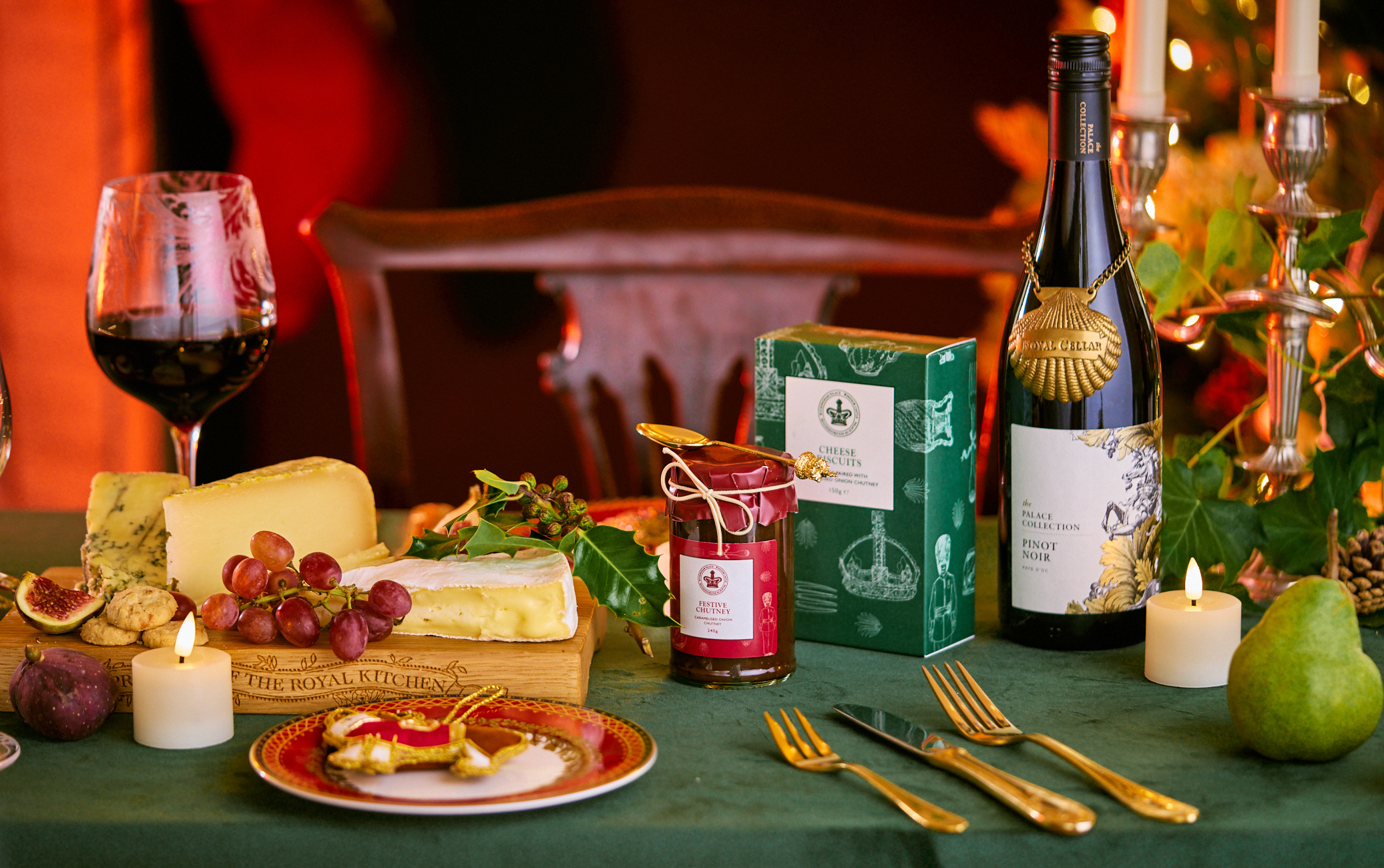Spread of Christmas items include wine glass filled with wine, wine bottle, cheese and chutney
