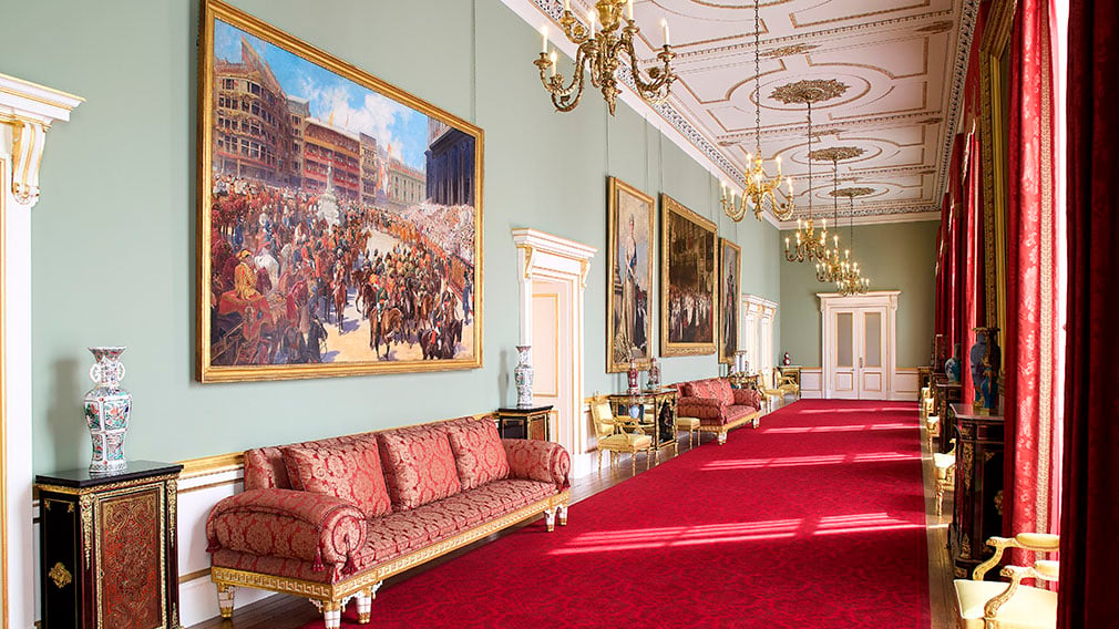 Room decorated with red carpets, paintings and chandeliers