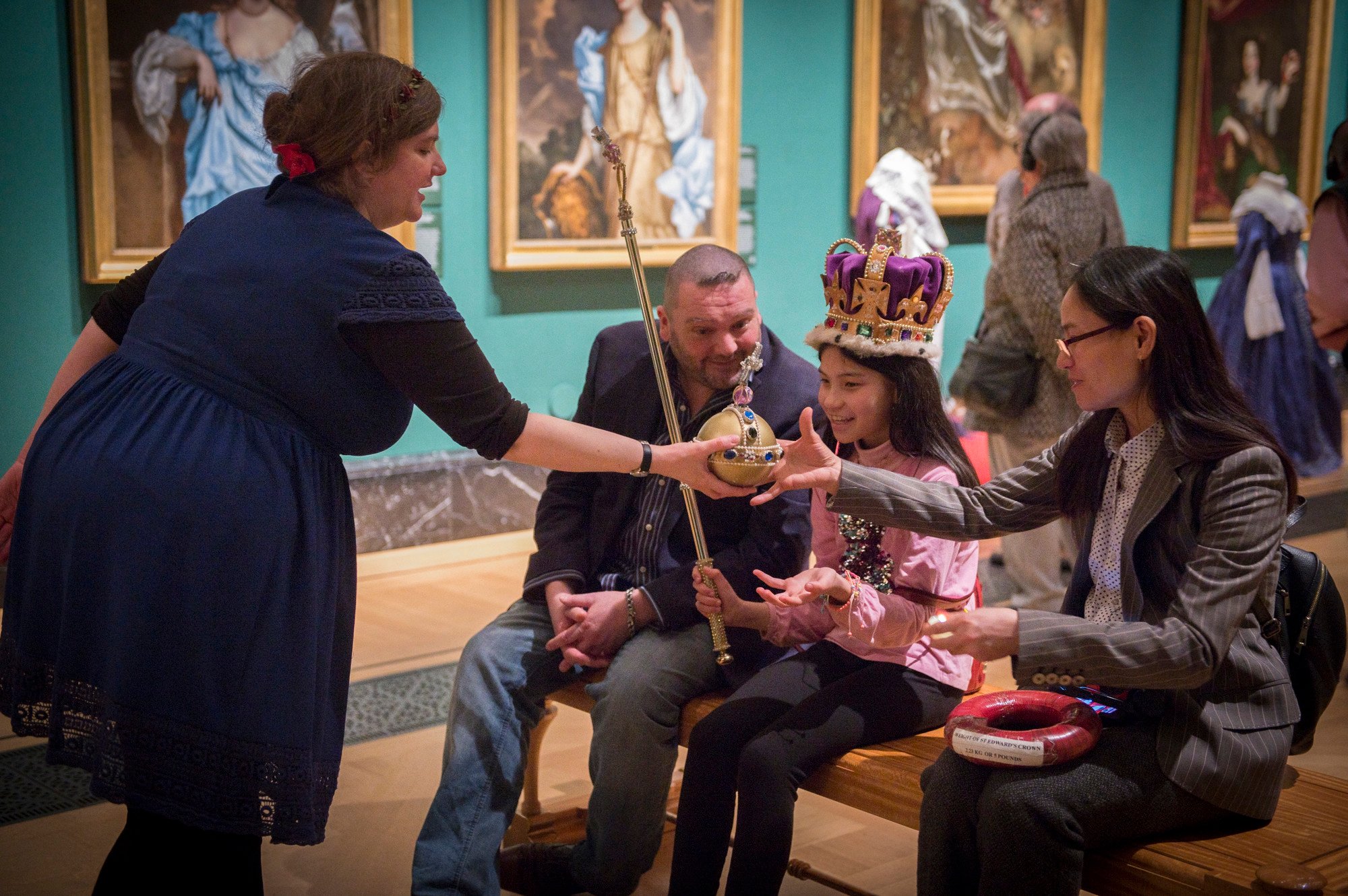 A family listen to a storyteller, whilst dressing up with a crown