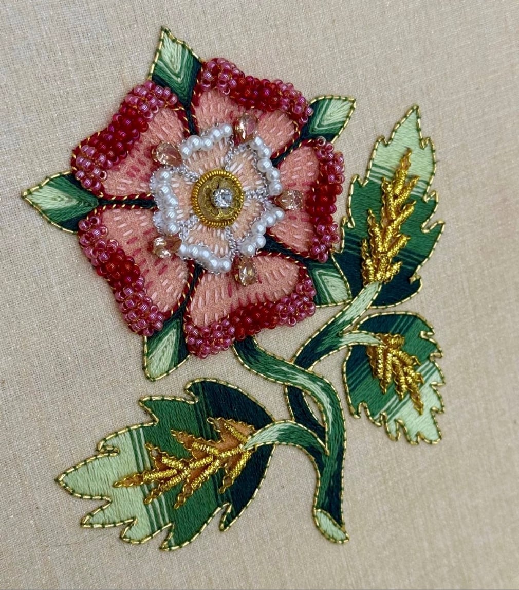 An embroidery of a rose on a beige fabric background