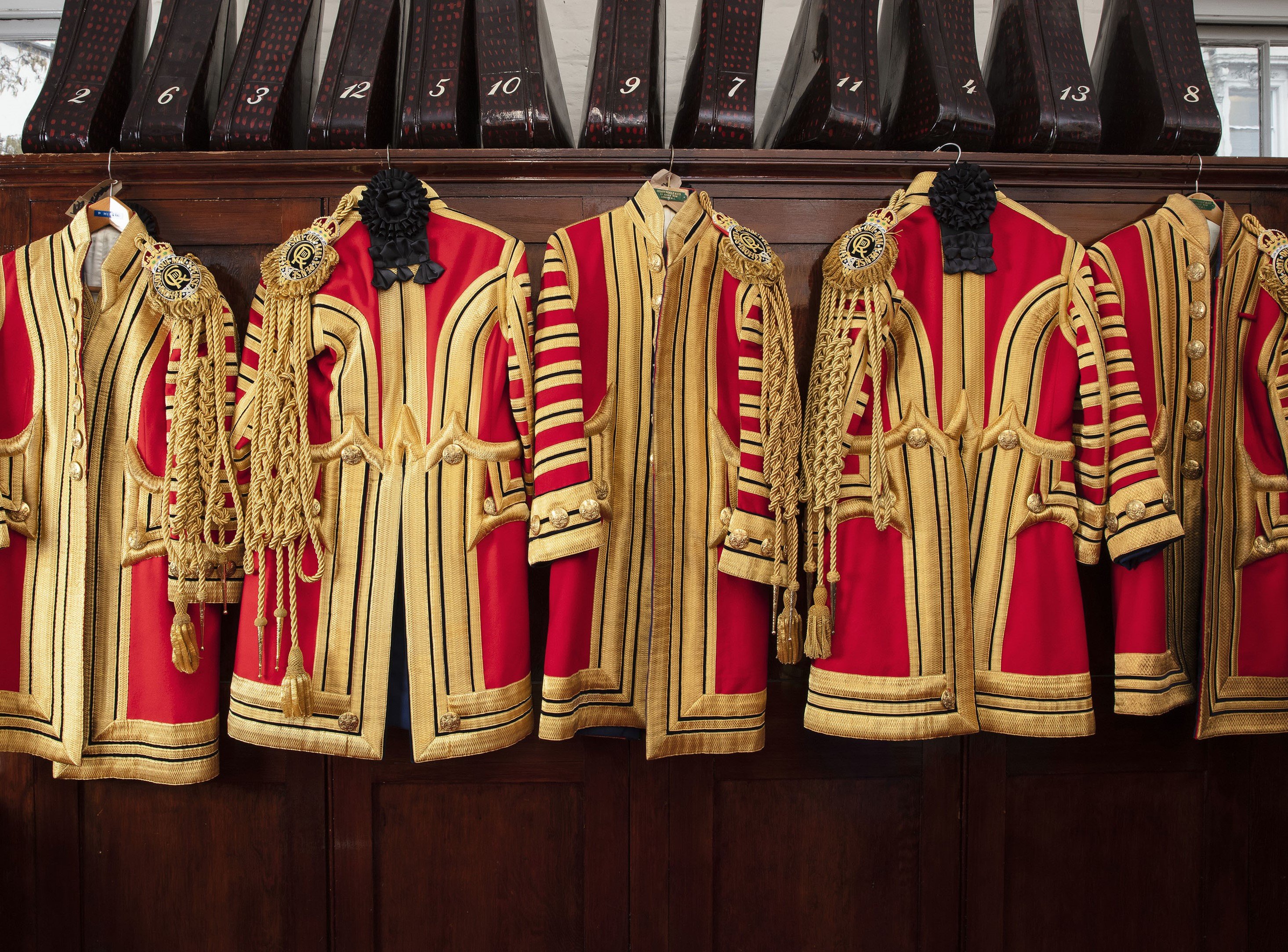Five red livery uniforms with black and gold hang up