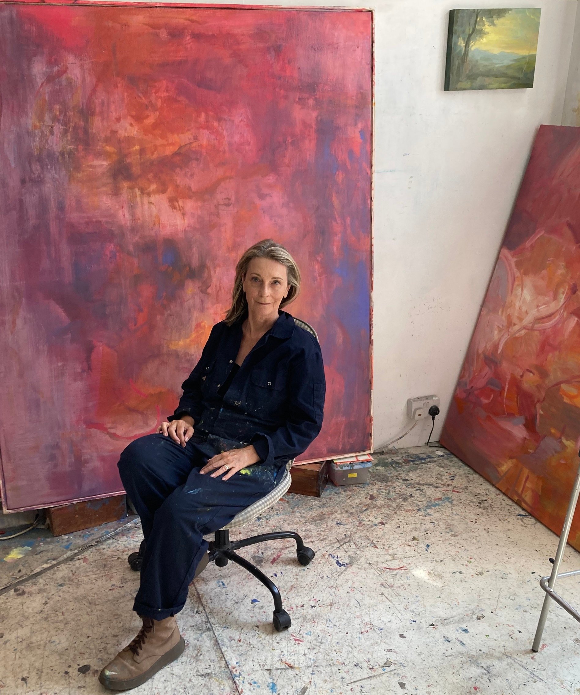 The artist Sara Lee Roberts sits in front of her paintings