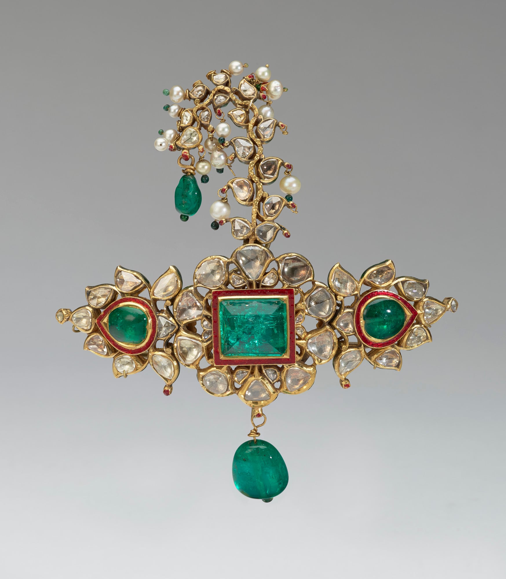 A turban ornament or sarpech comprised of emeralds and diamonds set within a gold frame, with additional emeralds and pearls suspended from it. 