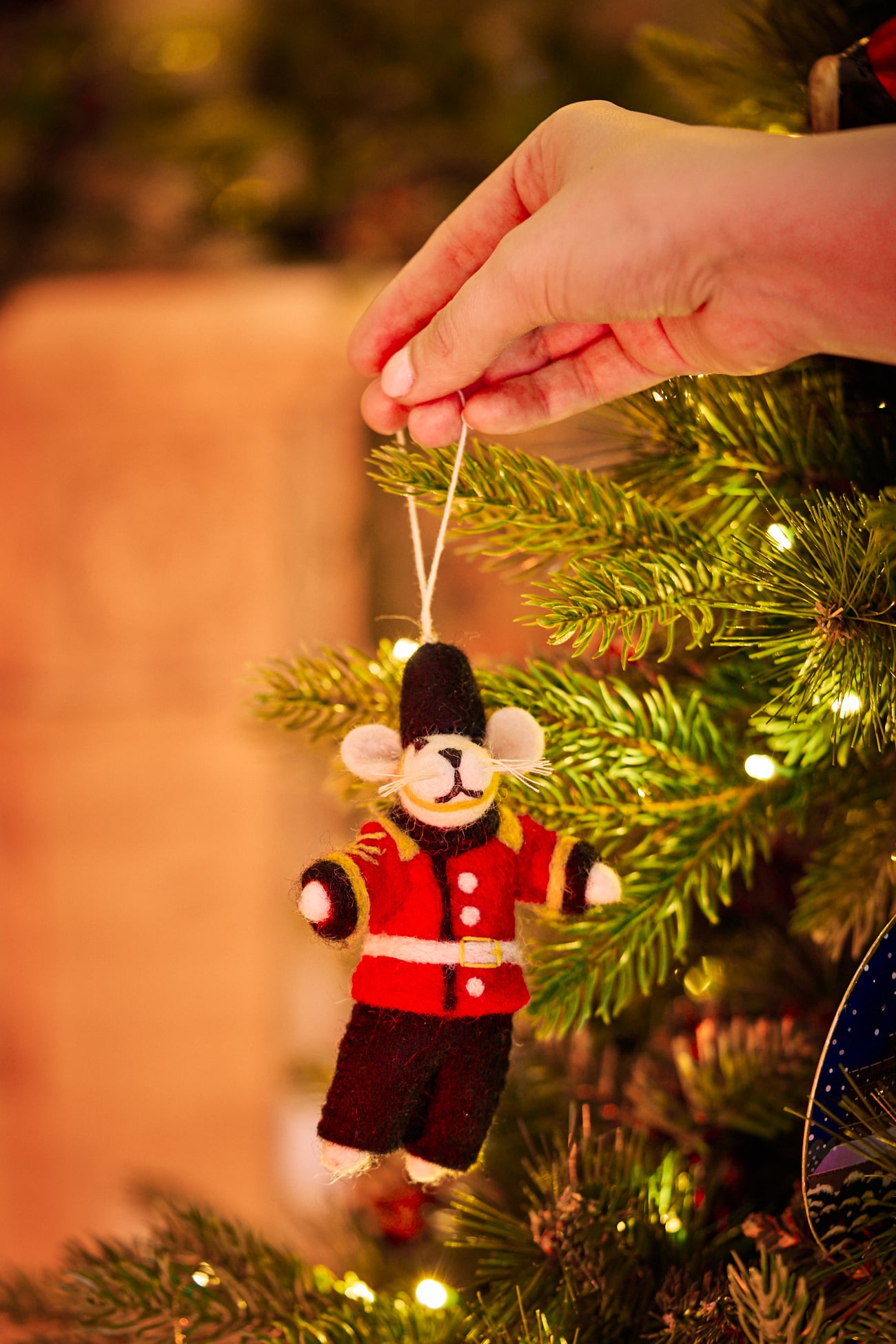 A felt tree decoration of The Guard Mouse is held up