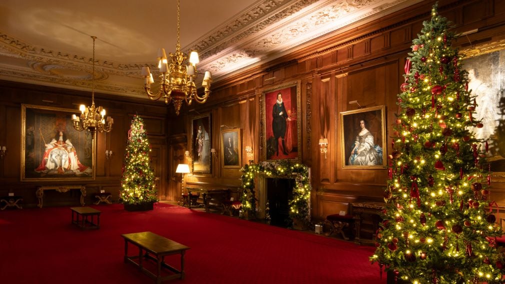 Christmas tree in a room with dark wood walls and paintings.