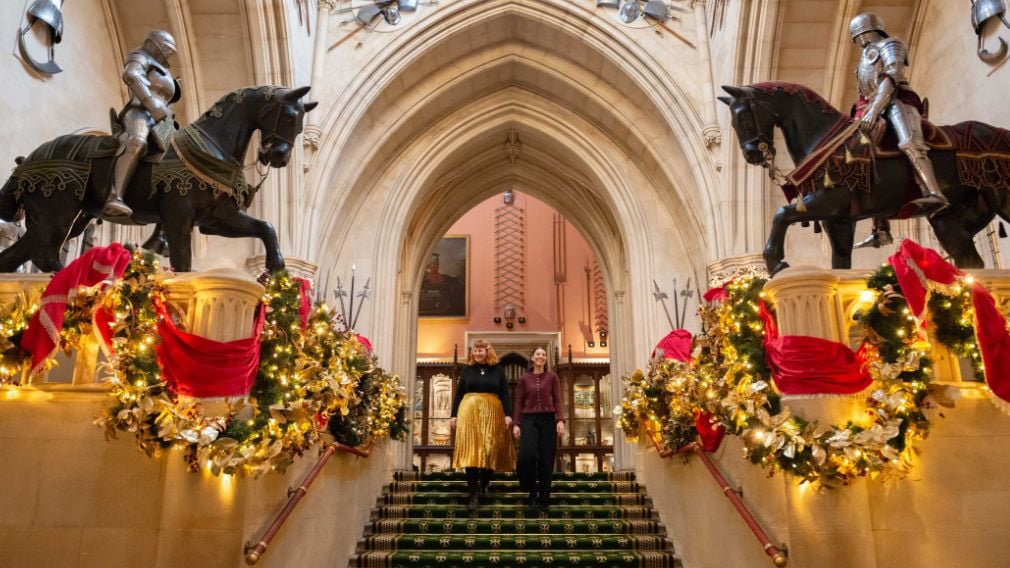 Christmas at Windsor Castle Two people walking down stairs which are decorated for Christmas.