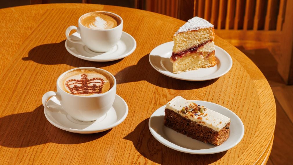 Two cups of coffee and two cakes on a table.
