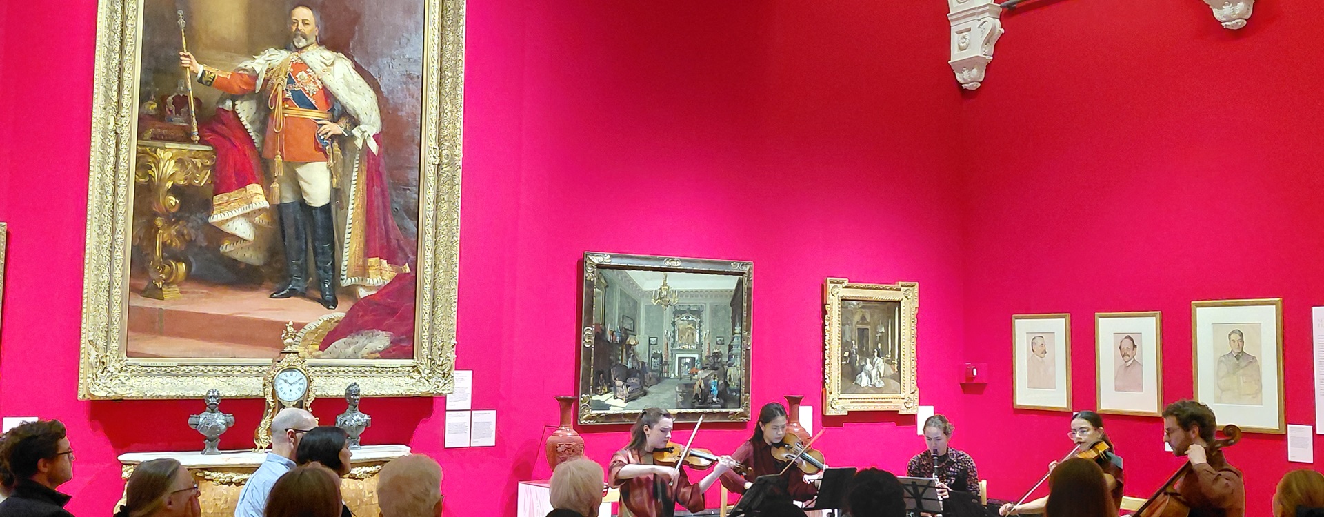 Musicians from the Royal College of Music performing in The King's Gallery, Buckingham Palace below a portrait of King Edward VII.