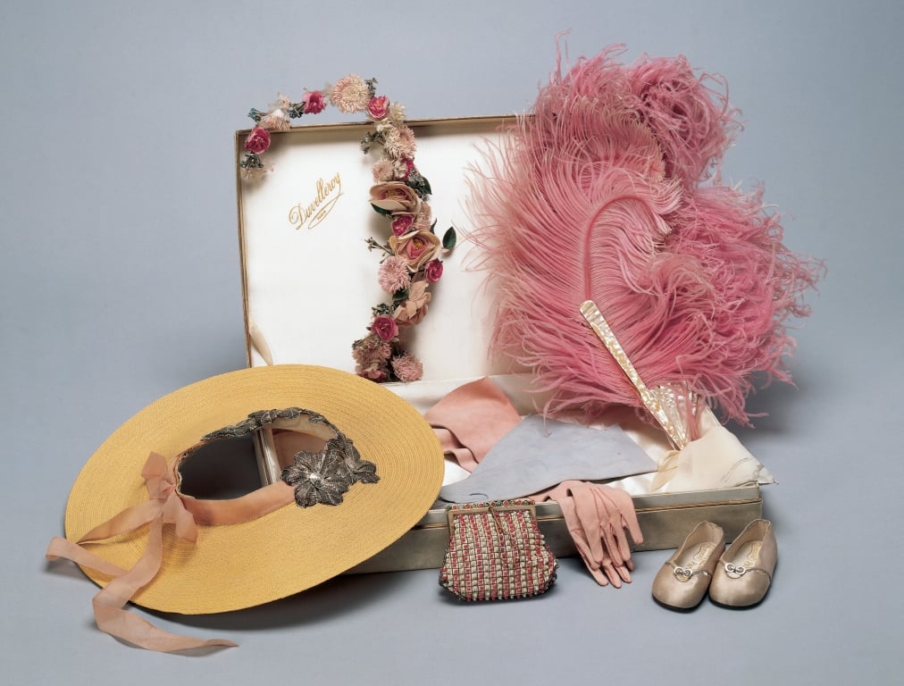 A pair of pale pink silk slippers with two silver buttons on the front of the shoe joined with a silver link and cut-out moons. With leather soles stamped with crosses.