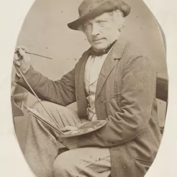 Photograph of a three-quarters length portrait of William Leighton Leitch facing the viewer, wearing a&nbsp;long jacket and hat, sitting in front of&nbsp;an easel.&nbsp;A&nbsp;paint palette rests on his left arm and he holds a paintbrush in his right hand
