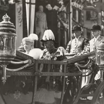 Photograph of King George V wearing a plumed bicorn hat and seated alongside Queen Mary who is wearing a fur stole as they ride in an open topped carriage through Temple Bar in London on their way to the Service of Thanksgiving at St Paul's Cathedral, as 