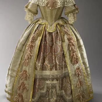 The most glamorous of all Queen Victoria&rsquo;s surviving clothes, this costume was inspired by the court of Charles II. The rich brocade of the underskirt was woven in Benares. The lace of the berthe is a copy of seventeenth-century Venetian raised-poin