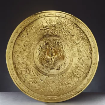 A silver-gilt convex shield with a central medallion cast in high relief showing Apollo in a quadriga, surrounded by stars and female figures representing the constellations. The broad border is cast in low relief with scenes of human life (a wedding and 