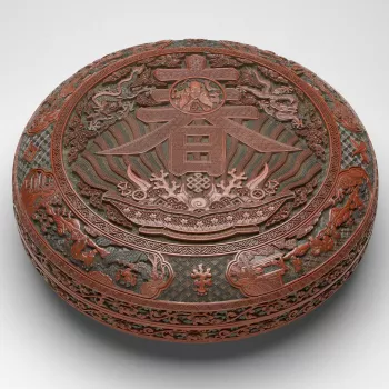 Large Imperial shallow box, with rounded sides and flanged rim, the matching cover with almost flat top. With many layers of ochre-yellow, green and red lacquer applied over a wood base. Carved on the top, a circular panel within a &lsquo;meander scroll&r