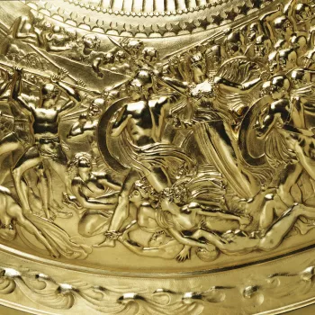 A silver-gilt convex shield with a central medallion cast in high relief showing Apollo in a quadriga, surrounded by stars and female figures representing the constellations. The broad border is cast in low relief with scenes of human life (a wedding and 