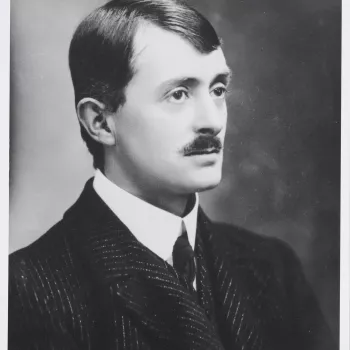 Photograph of a head and shoulders length portrait of the Poet Laureate and holder of the Order of Merit, John Masefield. He faces three-quarters right and wears a dark jacket, white shirt and tie.