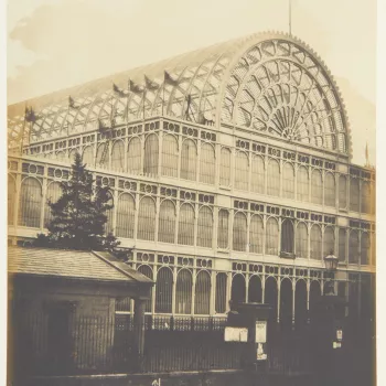 Photograph&nbsp;of an&nbsp;external view of the south transept of the Crystal Palace, Hyde Park during the Great Exhibition.&nbsp;Flags fly along the building and top of&nbsp;the arched roof. 


This photograph is from Volume II (RCIN 2800001) of ' Exhibi