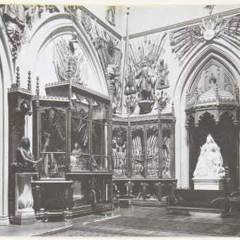 Photograph of the&nbsp;Grand Vestibule, with Boehm's statue of Queen Victoria&nbsp;with&nbsp;a collie (RCIN 35336)&nbsp;under a wooden Gothic canopy. The walls are lined with Gothic display cabinets filled with mostly weapons; above them are displays of a