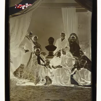 Glass plate negative of a full length group portrait of royal family members taken after the wedding of Prince Albert Edward (1841-1910) and Princess Alexandra (1844-1925). The family are posed around a bust of Prince Albert. The sitters include Princess 