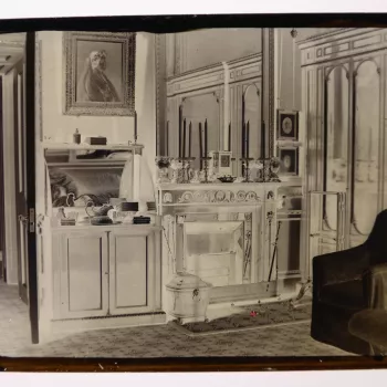 Glass plate negative of the Prince Consort's Dressing Room in the Private Apartments, Windsor Castle (F208). There is a black marble fire place (RCIN 79838), with a set of fire irons; and overmantel mirror and mantel with four candlesticks, vases and a cl