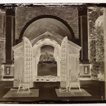 Glass plate negative of the wooden shrine to Prince Albert (1819-61) inside the Royal Mausoleum, Frogmore. The doors of the construction are open so that the prince's sarcophagus and effigy are visible. The base of the tomb is covered with wreaths.
The sh