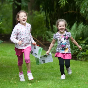 Two children running through a garden area