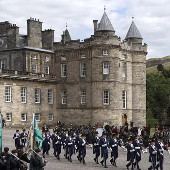 The exterior of the Palace of Holyroodhouse. A ceremony of guards parade outside.