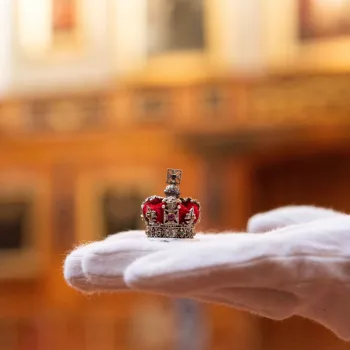 A tiny crown is held by the curator of the special display for the centenary of Queen Mary’s Dolls’ House at Windsor Castle