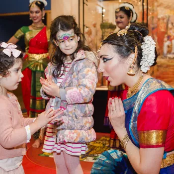 Children taking part in a dance lesson with a lady in traditional Indian dress