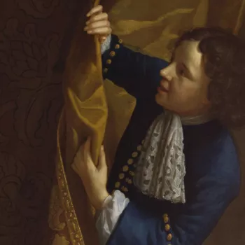 boy in blue looking around a curtain
