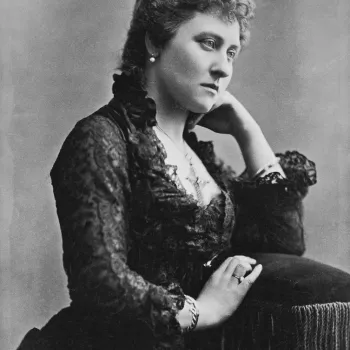 3/4 length of Princess Louise seated, left arm on back of her chair, left hand by her neck. She wears cross round her neck.