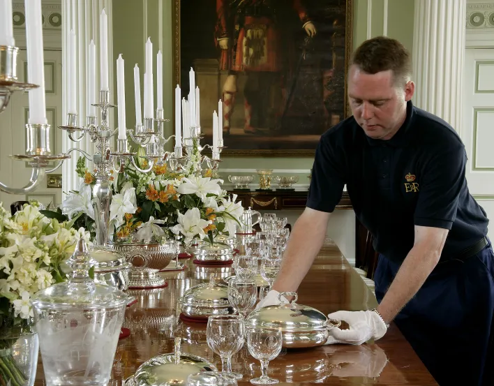 Palace attendant setting up royal banquet in the dining room at Palace of Holyroodhouse