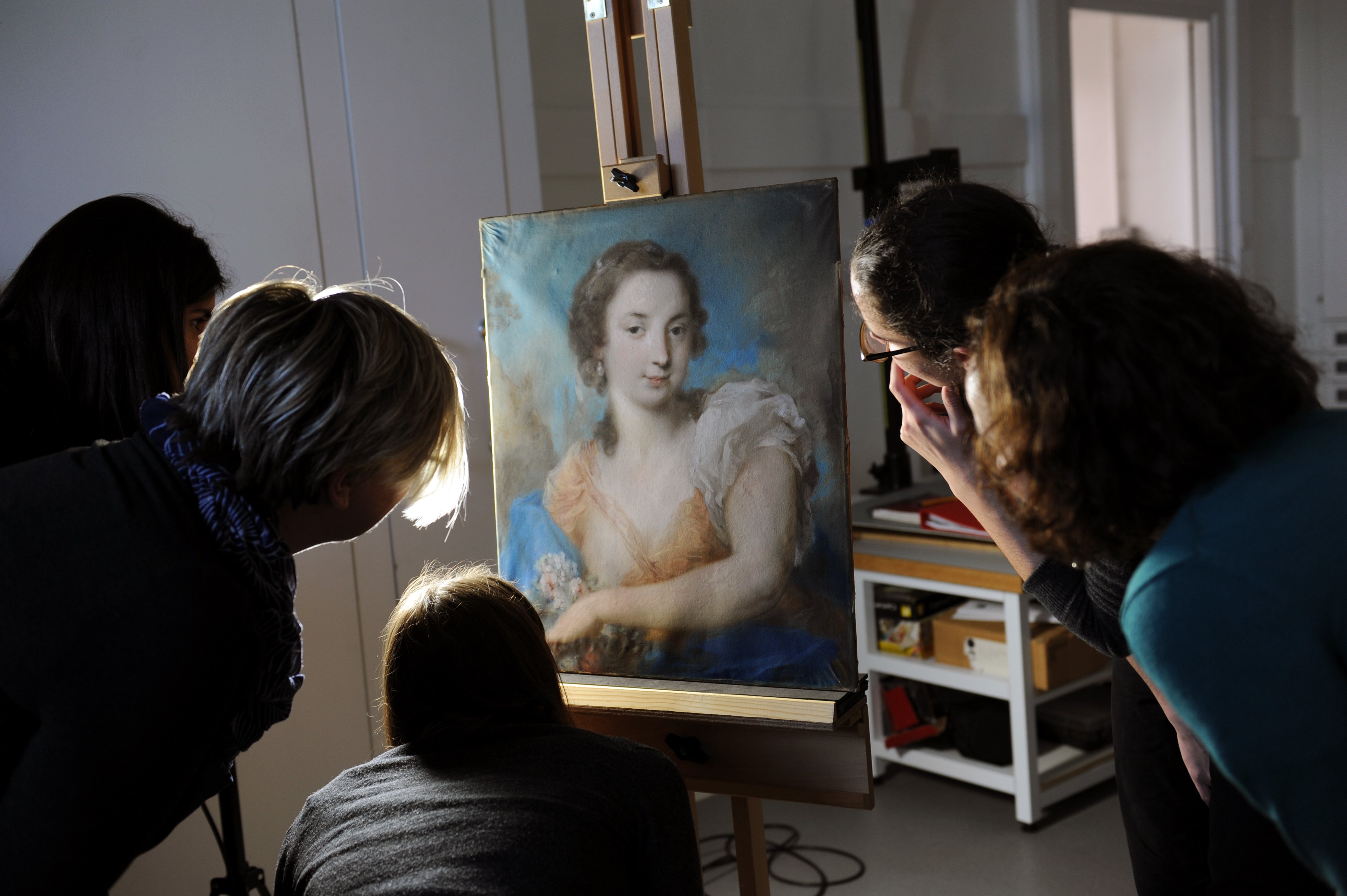 Conservation team examining pastel out of its frame